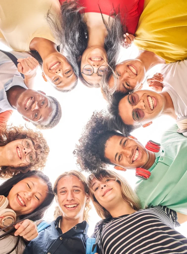 A group of people in colorful clothing stand in a circle smiling down at the camera