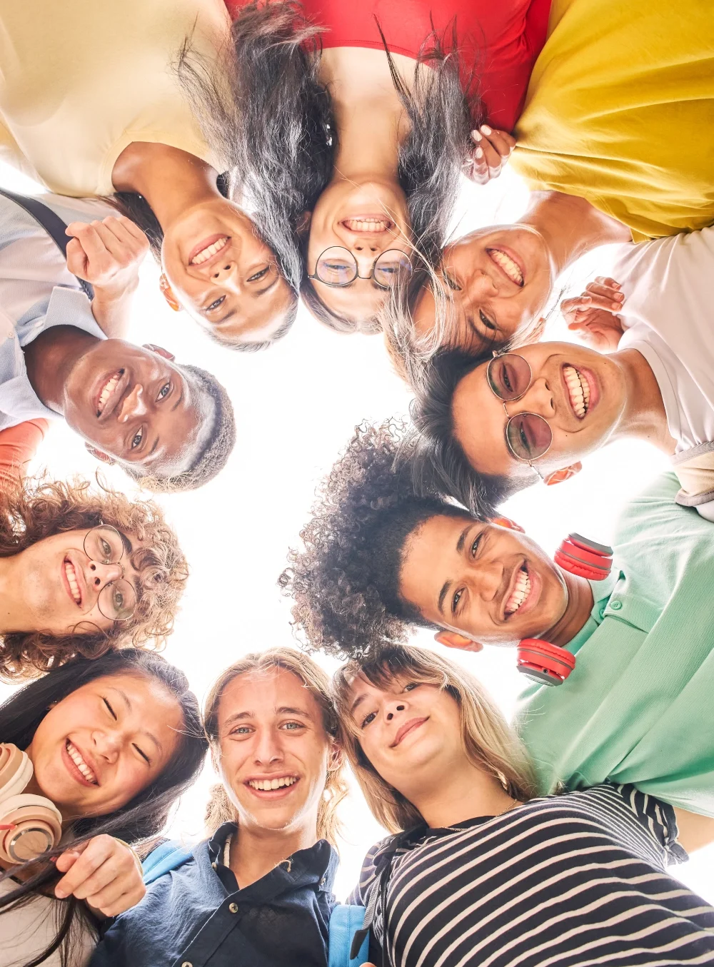 A group of people in colorful clothing stand in a circle smiling down at the camera