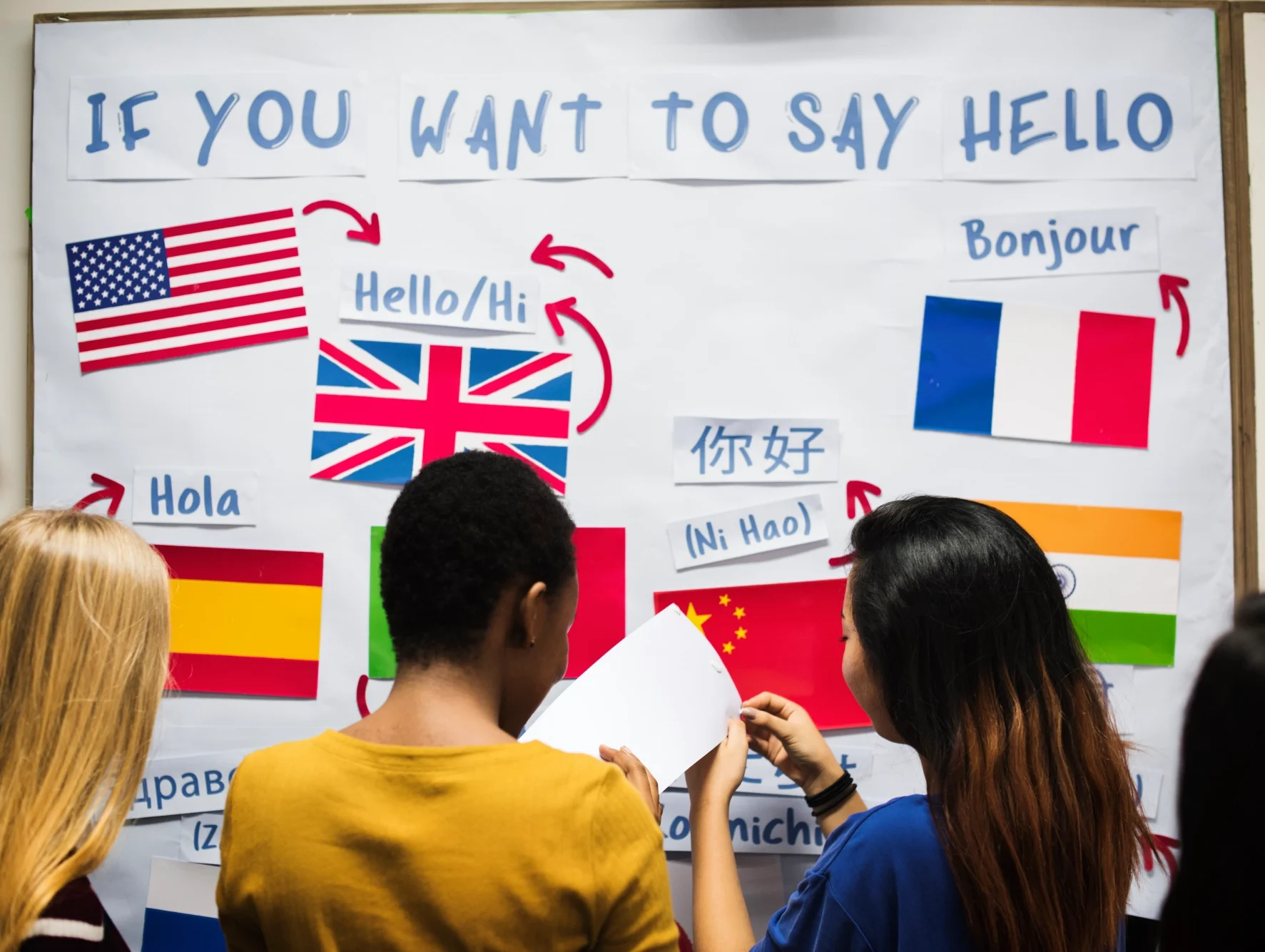 Students gather around a bulletin board with "hello" in different languages