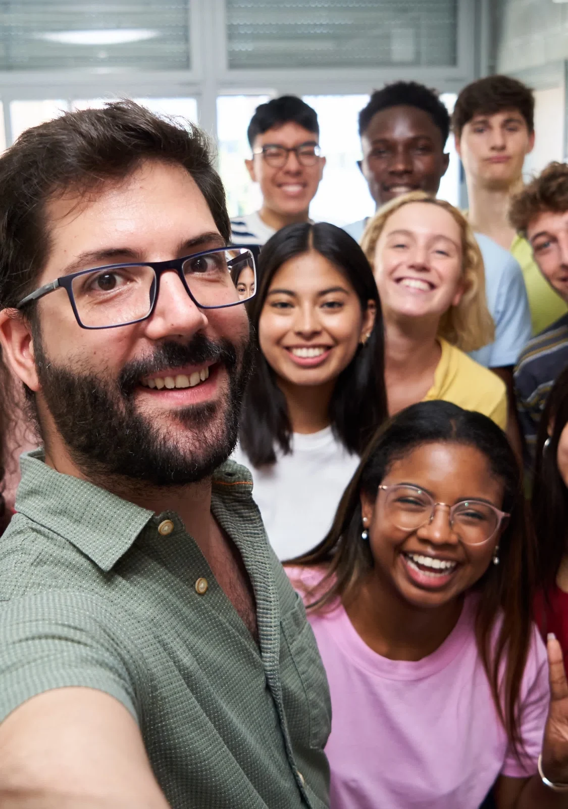 A teacher takes a selfie with a group of students in school